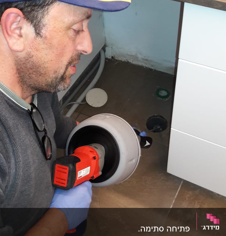 אדם עם כלי עבודה לפתיחת סתימות בצנרת